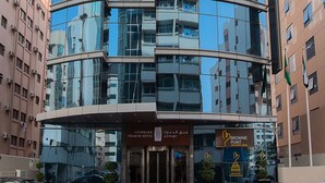 A modern hotel with a curved glass facade, multiple balconies, and a prominent entrance with signage. - Landmark Premier Hotel (Dubai)