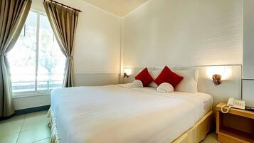 Una camera d'albergo con un letto grande, tende, un comodino con una lampada e una finestra con tende.