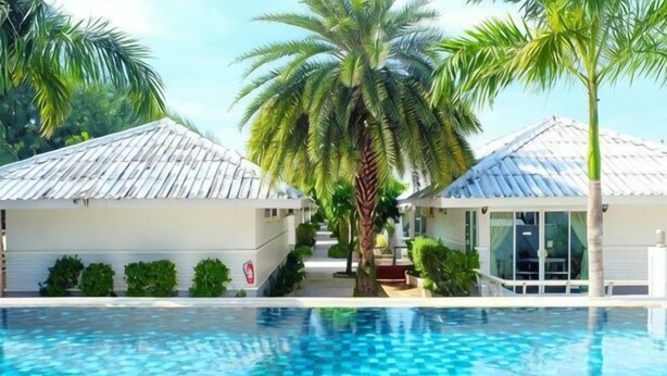 A swimming pool with palm trees, a covered area, and a building with a white exterior. - Laemsing Natural Beach Resort (Laem Sing)