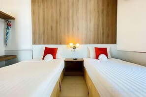 Een hotelkamer met twee bedden, een houten hoofdeinde, bedlampen en een klein nachtkastje.