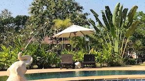 A swimming pool with a water fountain, surrounded by lush greenery and a large elephant statue. - Papai Country Lodge (Doi Saket)