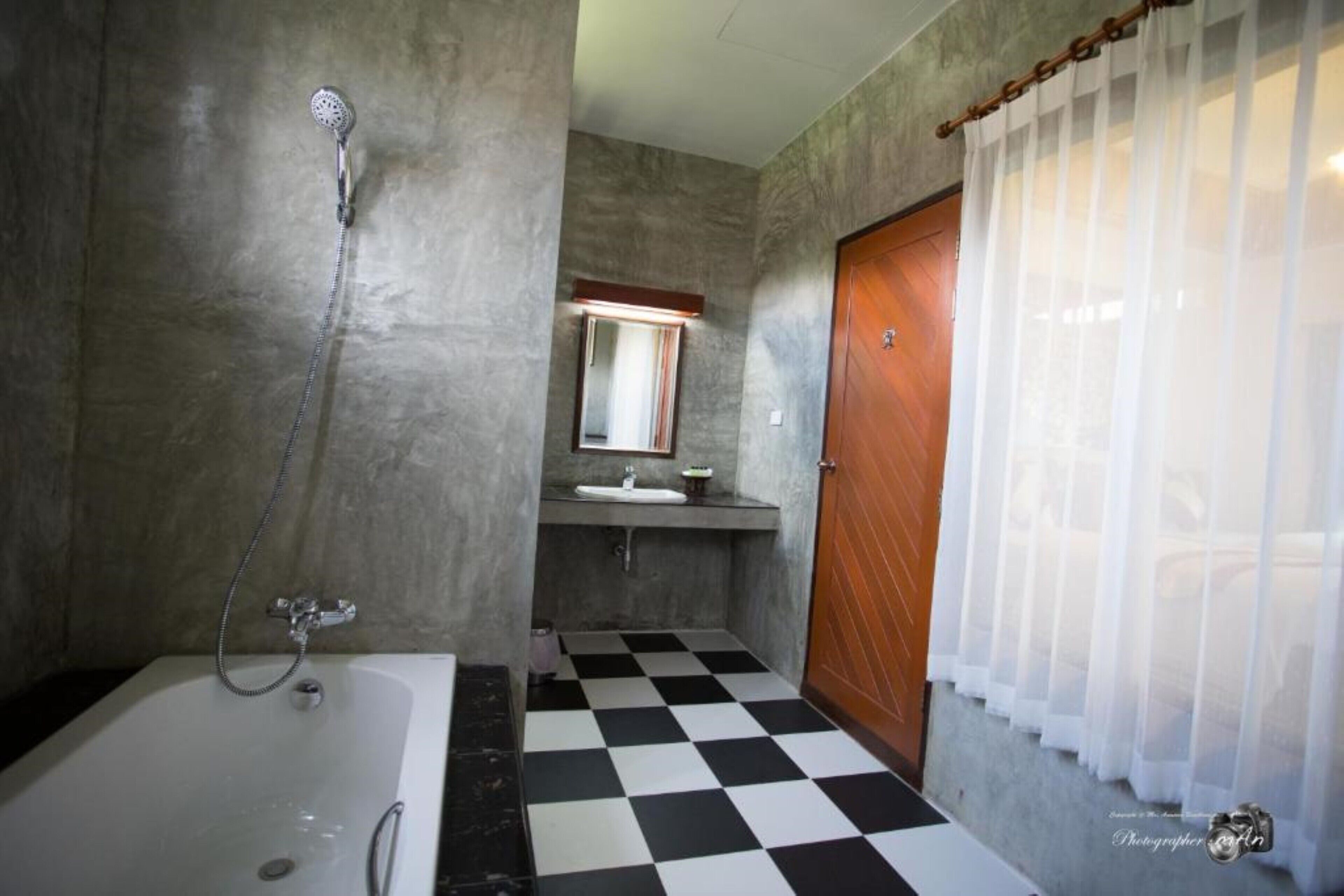 A bathroom with a checkered floor, a bathtub, a shower, a sink, and a mirror.