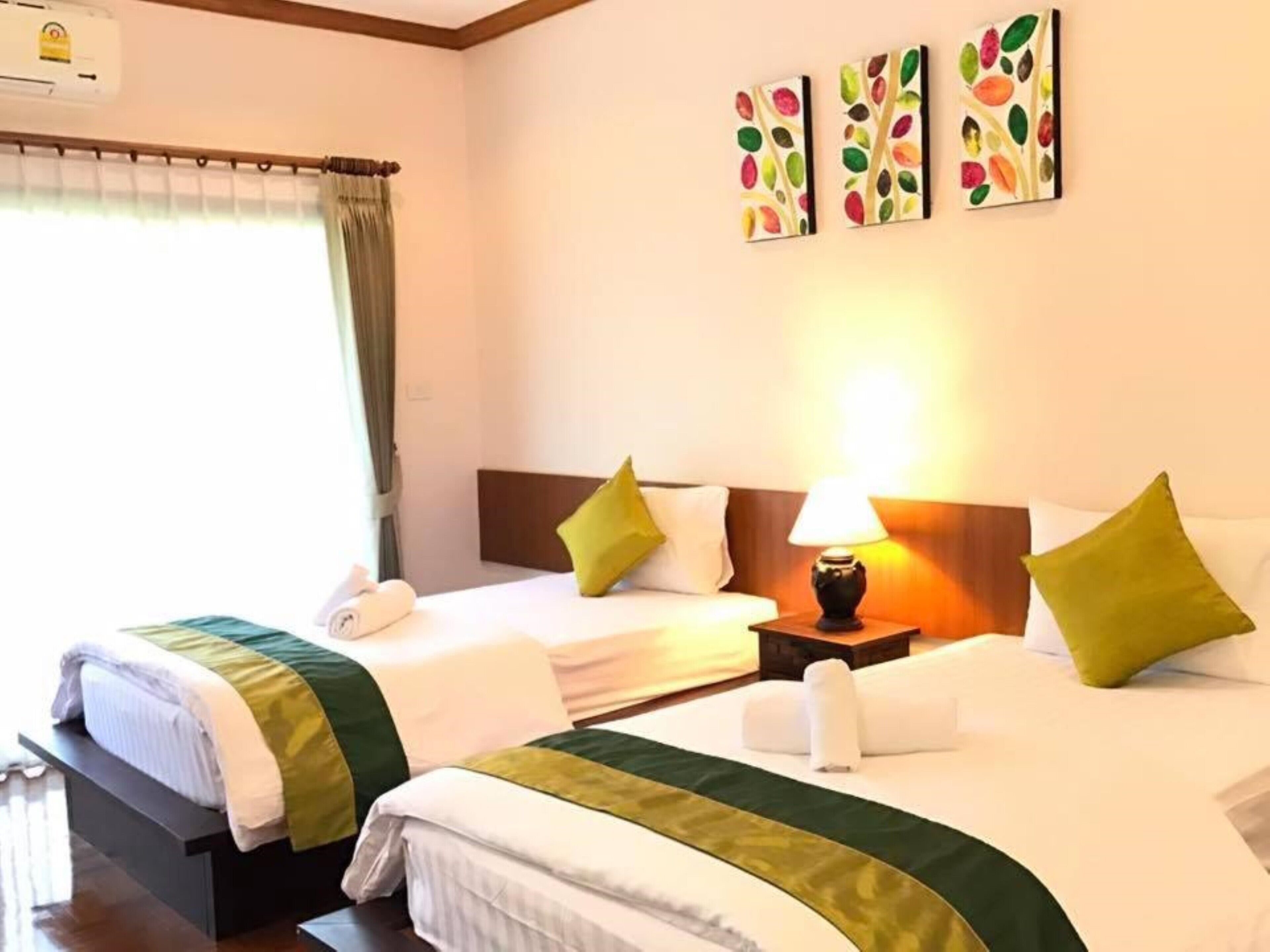 A hotel room with two beds, a nightstand with a lamp, and artwork on the wall.