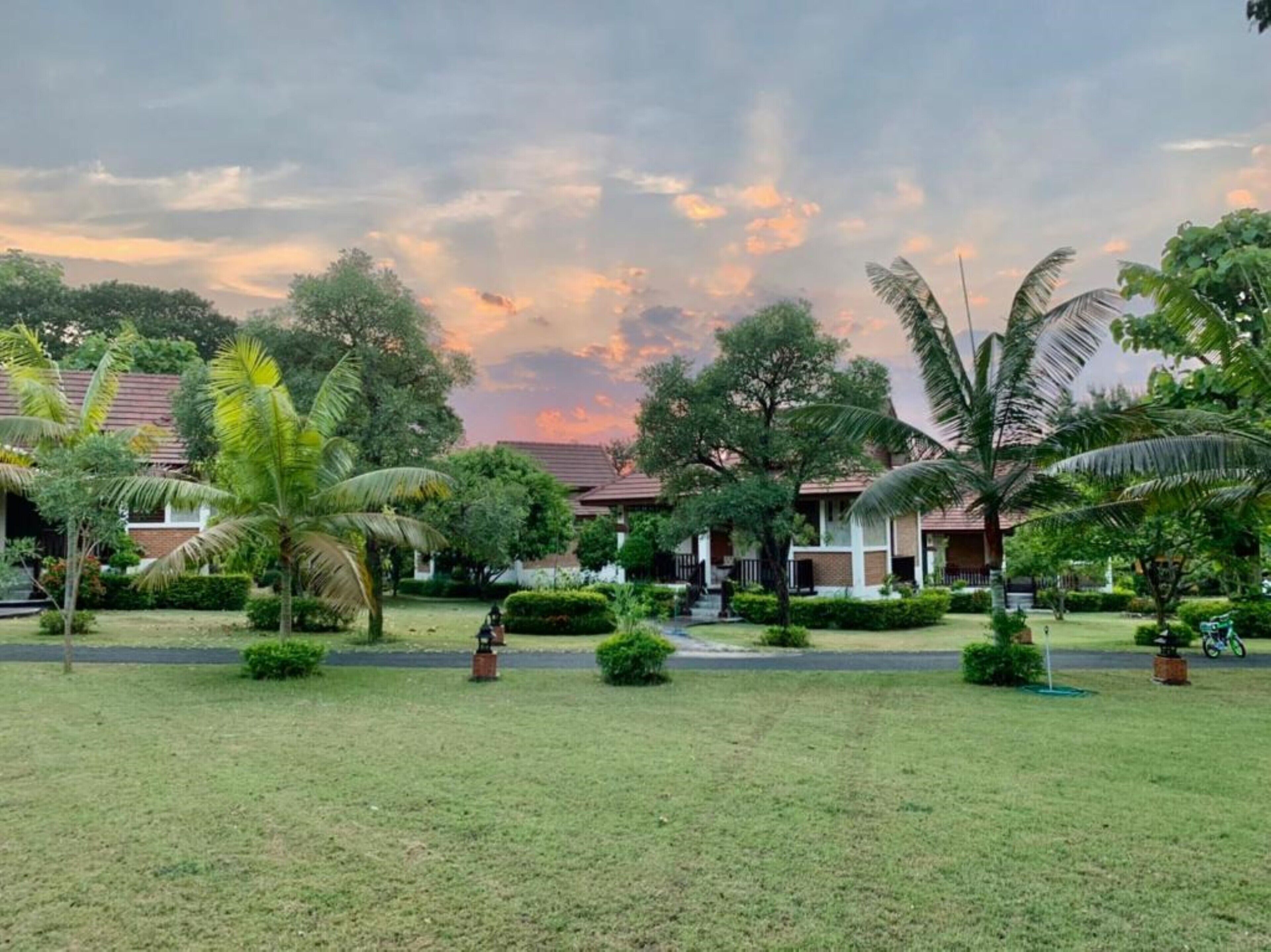 A resort with multiple bungalow-style buildings, a well-maintained lawn, and palm trees.