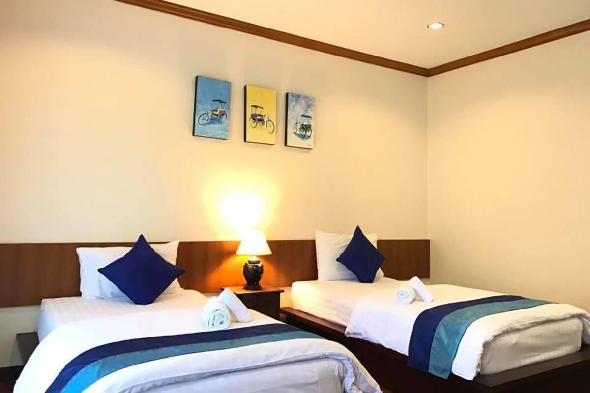 A hotel room with two beds, a nightstand with a lamp, and three wall-mounted pictures of bicycles.