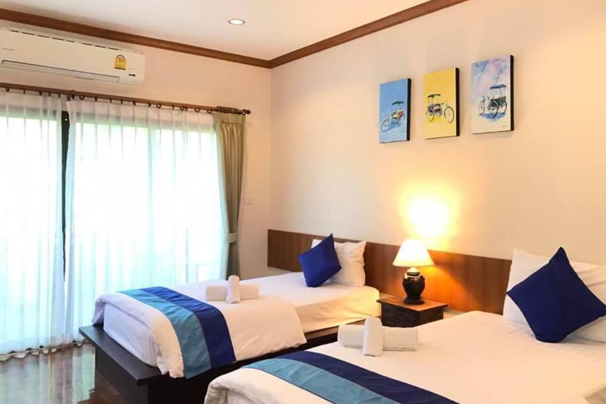 A hotel room with two beds, a nightstand with a lamp, and artwork on the wall.
