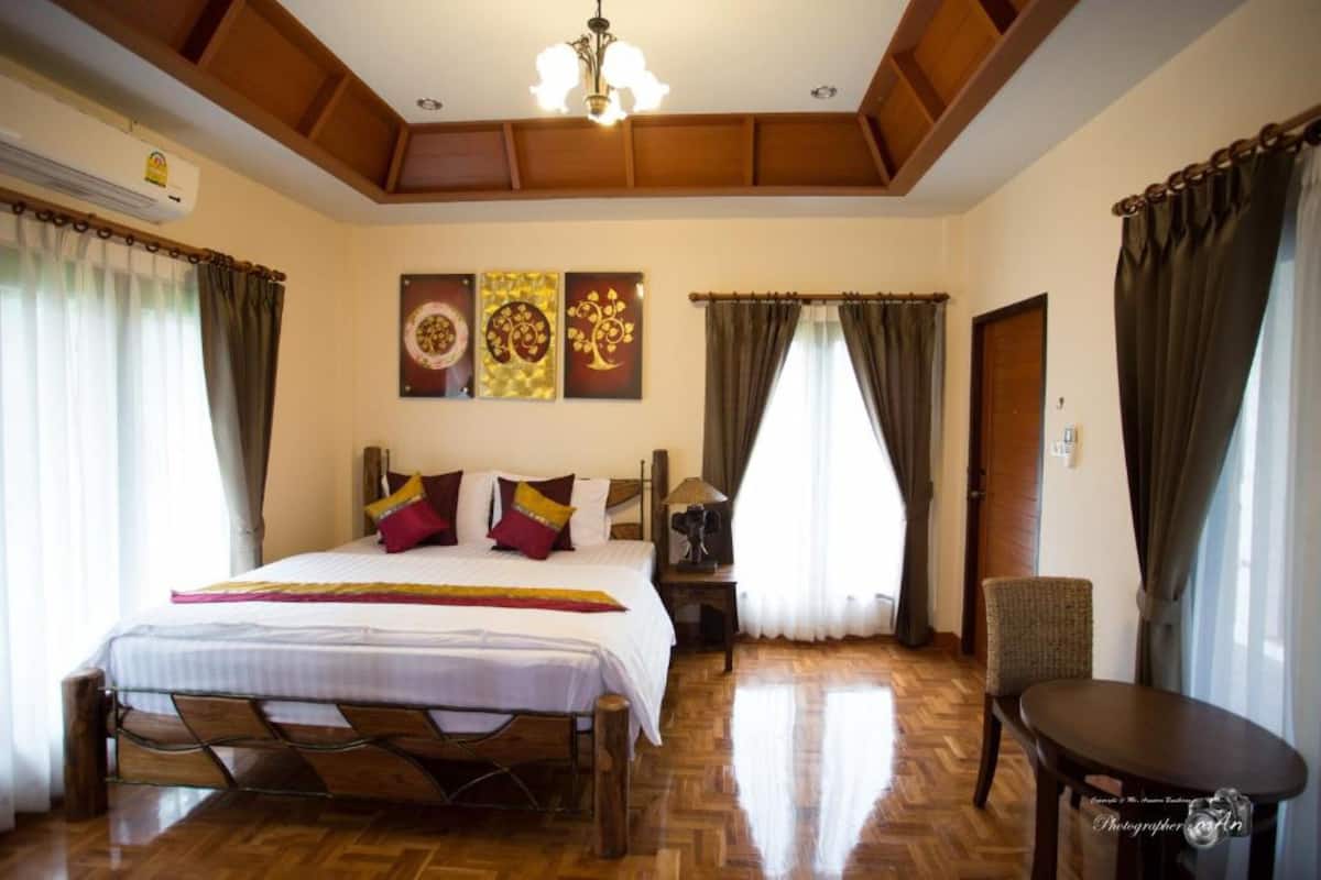 A hotel room with a wooden bed, a nightstand, a chair, and a table.