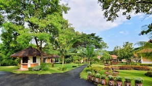 A pathway leading to a small building with a tiled roof, surrounded by lush greenery and palm trees. - Papai Country Lodge (Doi Saket)