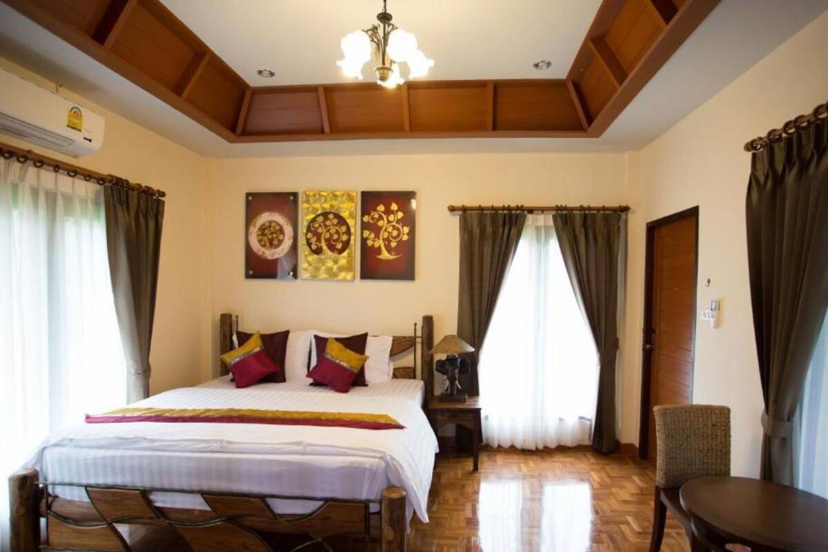 A hotel room with a large bed, a chair, a nightstand, and a ceiling fan.