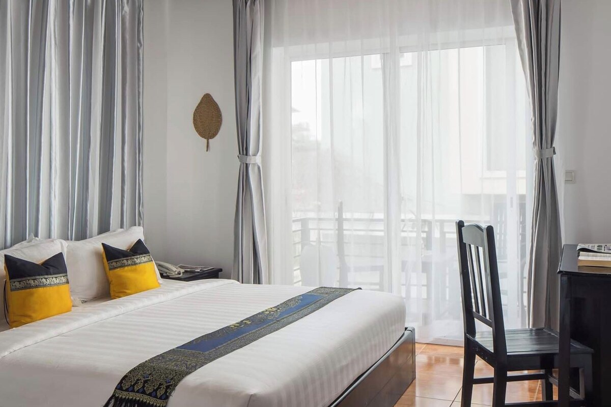 A hotel room with a bed, a desk, and a chair.