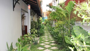 A narrow pathway with a checkered pattern leading to a building entrance, surrounded by various tropical plants. - Golden Orchid Angkor (Siem Reap)