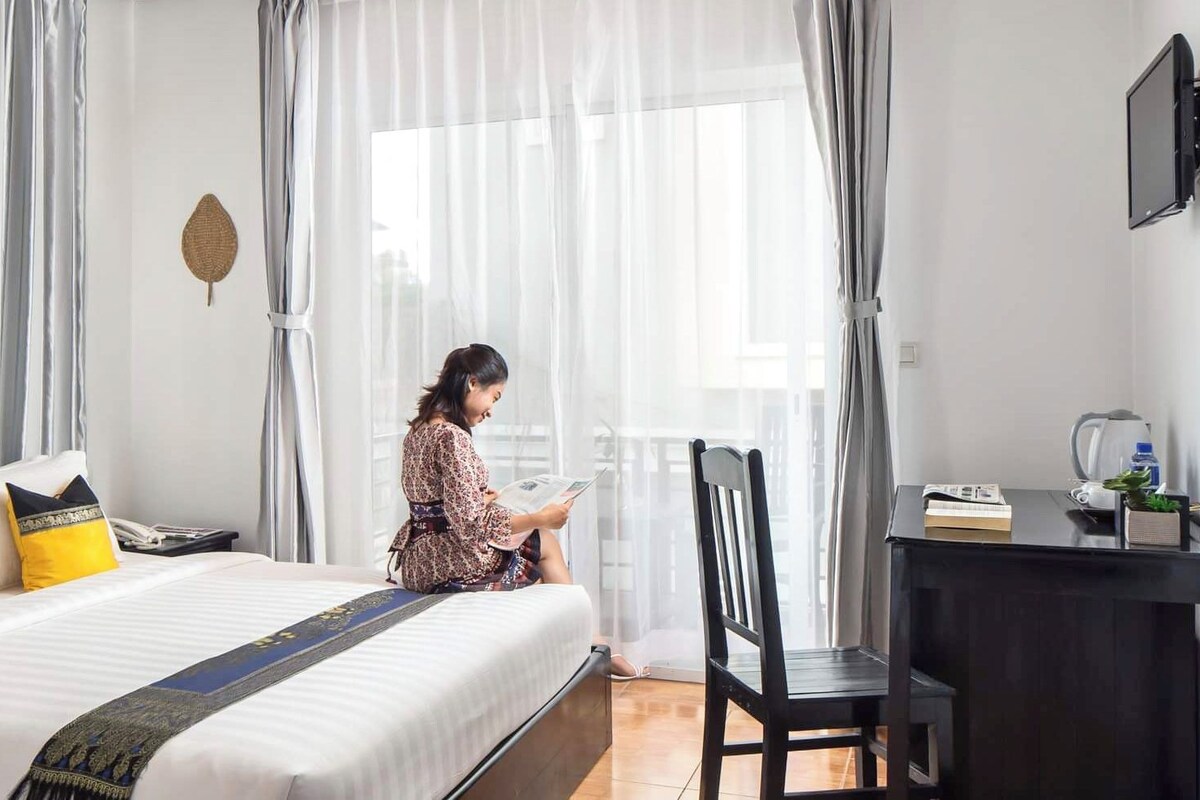 A hotel room with a bed, a desk, a chair, and a television.