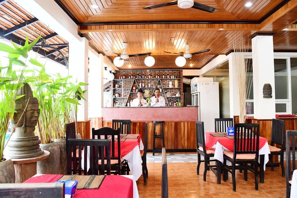 Un restaurante con techo de madera, mesas con manteles rojos y sillas.