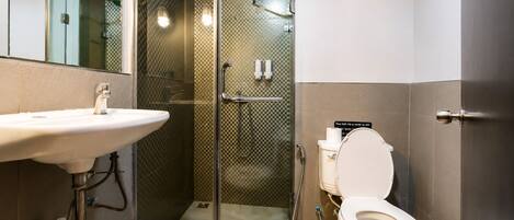 Un baño moderno con ducha de vidrio, lavamanos e inodoro.