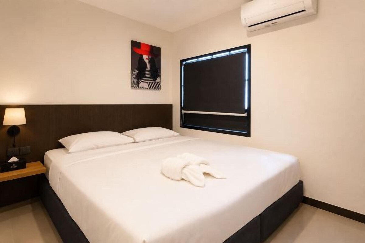 Una camera d'albergo con un letto, un comodino, una lampada e un condizionatore d'aria a parete.
