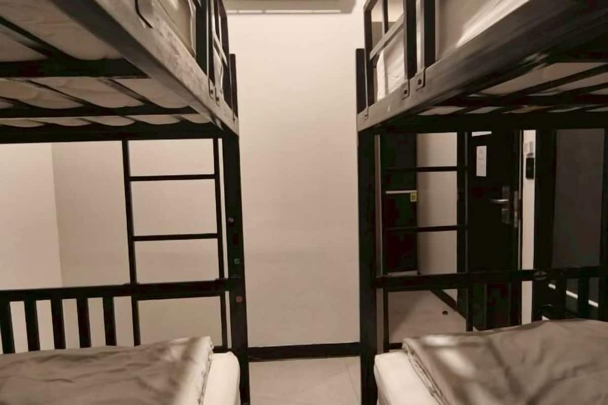 Une chambre avec un lit superposé, une porte centrale, une petite fenêtre et un placard visible.