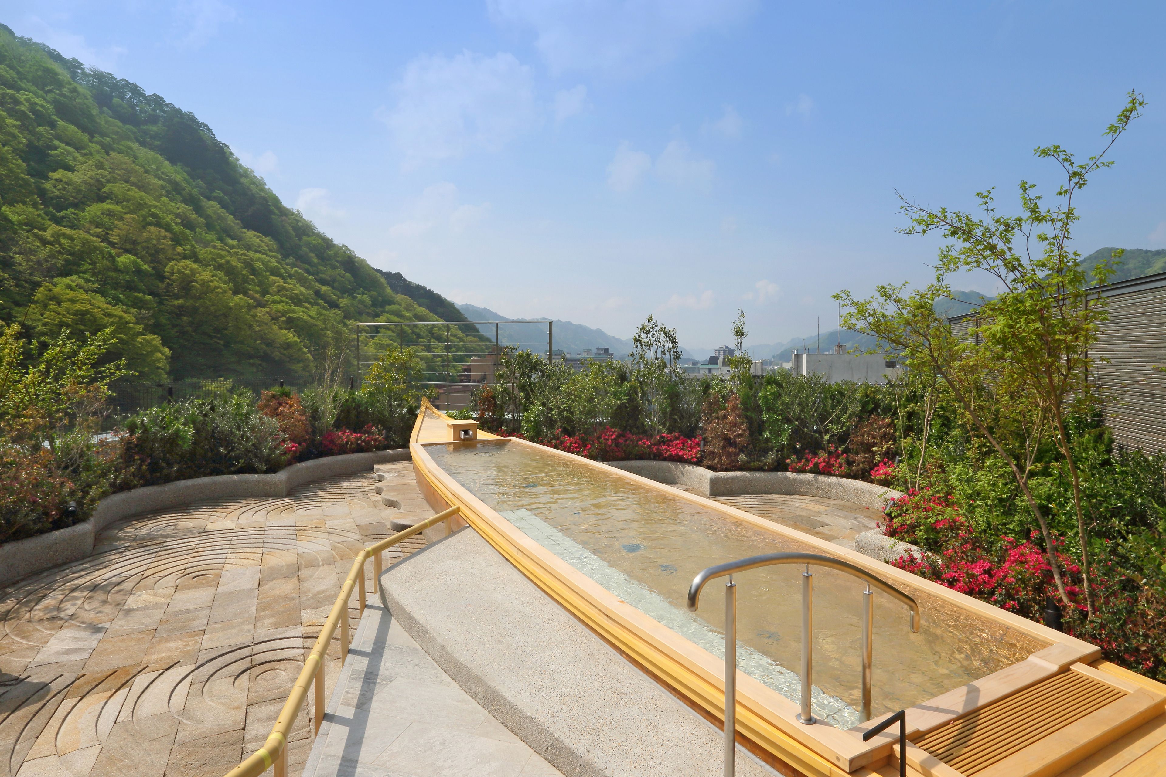A hot spring area with a stone pathway leading to a wooden deck.