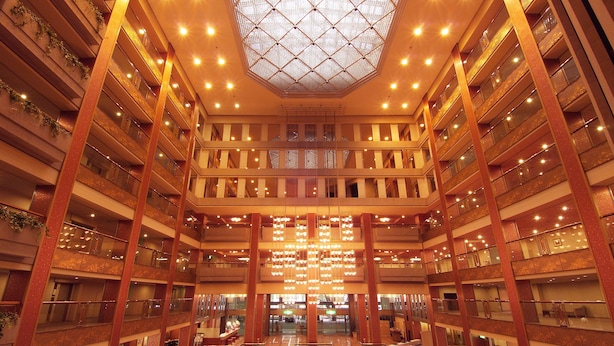 Um átrio com vários níveis, claraboia central, múltiplas varandas e interior espaçoso.