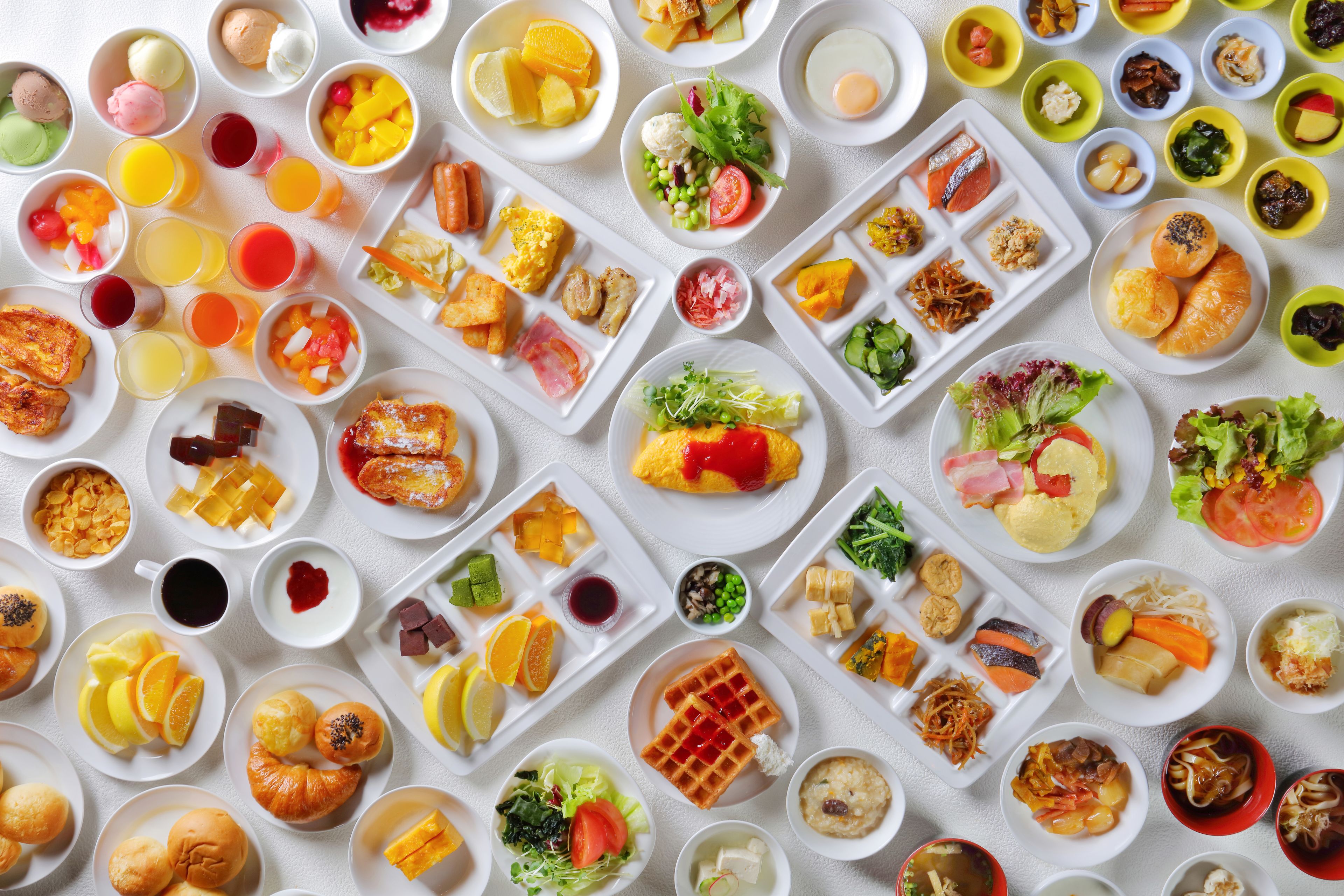 A variety of breakfast dishes including waffles, pastries, and fruits.
