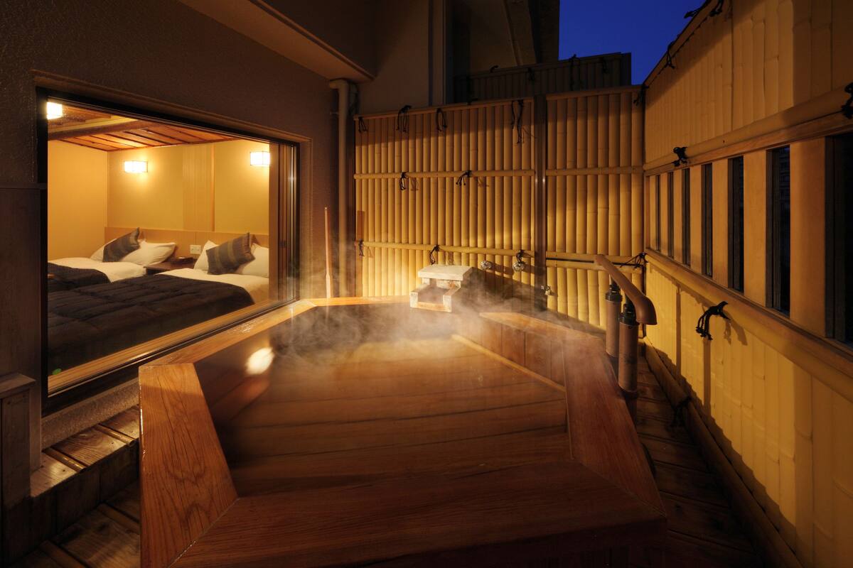 Un espace de baignade dans une source thermale, avec des bancs en bois et une cloison en bois.