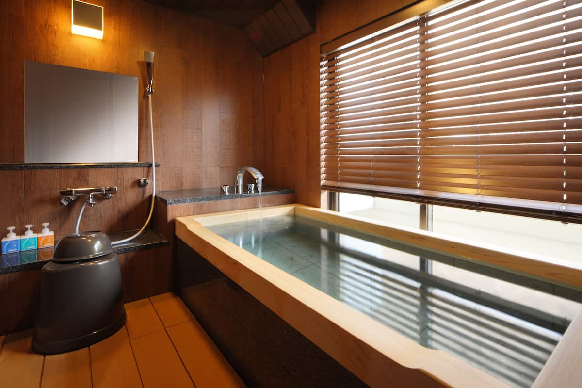 Une salle de bain moderne dotée d’un jacuzzi entouré de parois en verre, d’une douche et de toilettes.