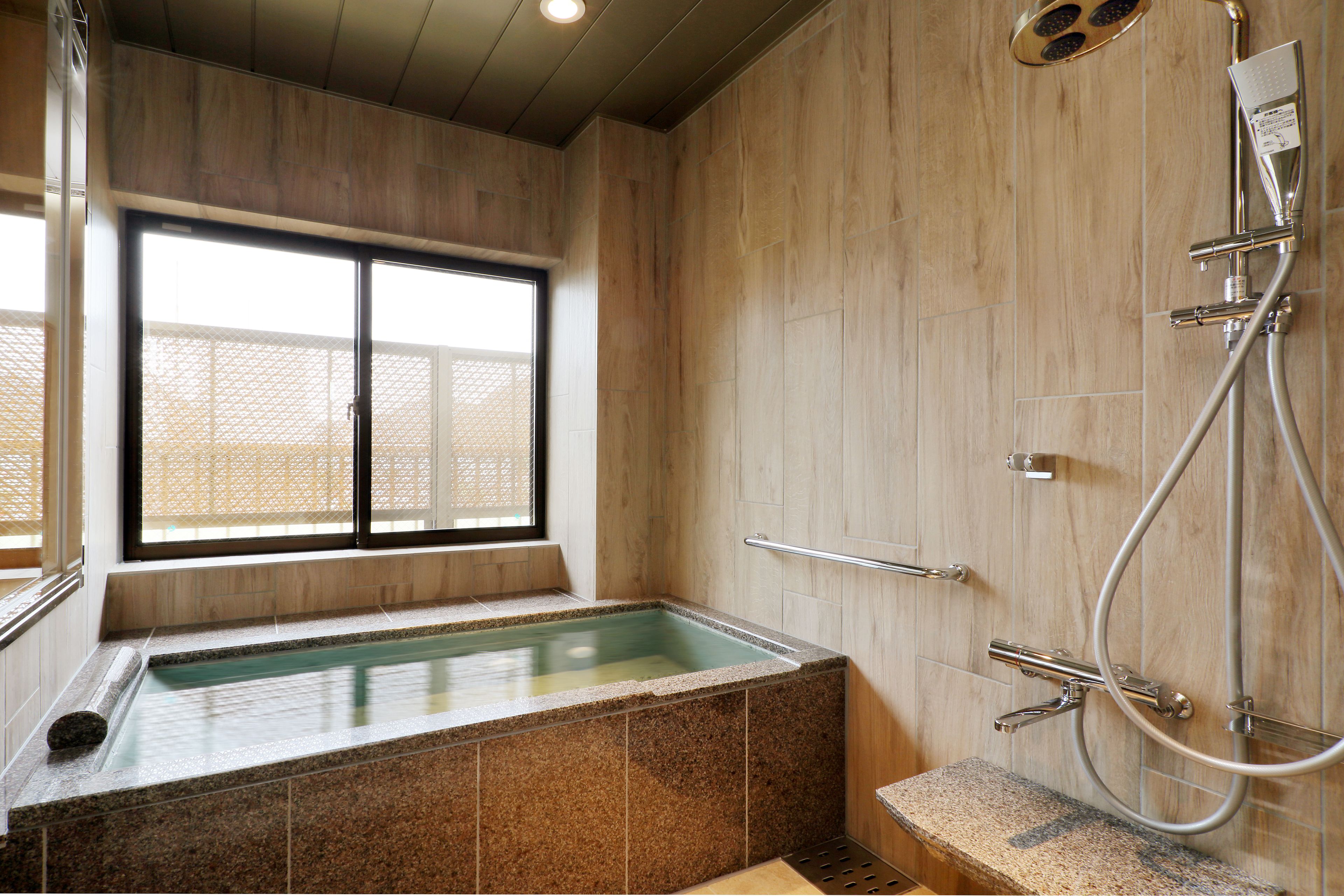 A modern bathroom with a freestanding bathtub, a shower, and a window providing natural light.
