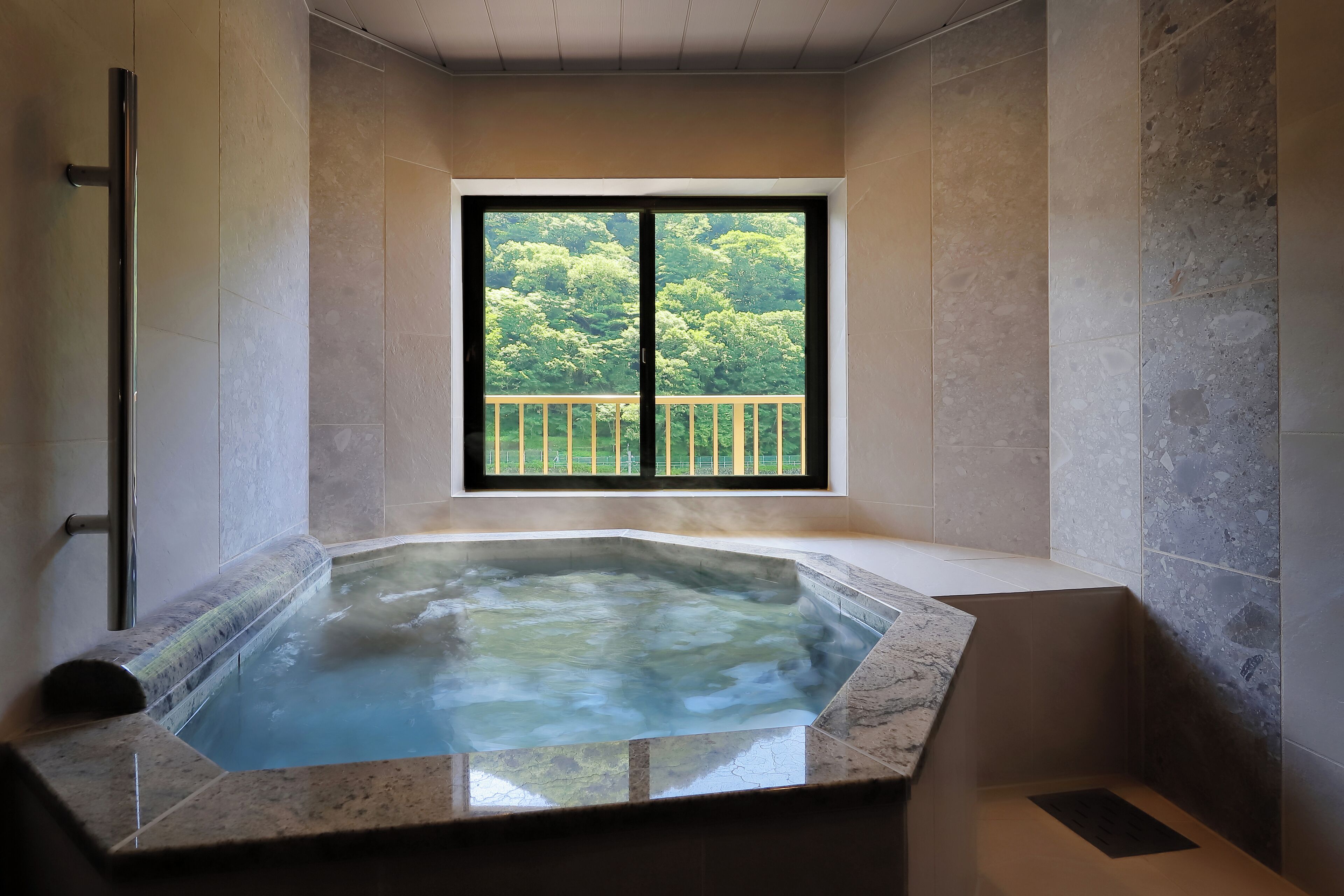 A modern bathroom with a glass-enclosed hot tub, a window with a balcony view, and a shower area.