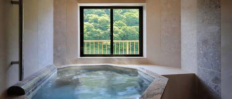 A modern bathroom with a glass-enclosed hot tub, a window with a balcony view, and a shower area.