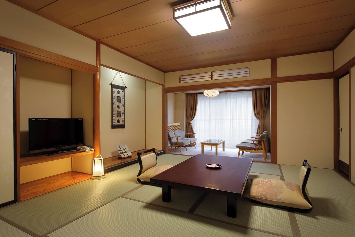 Une pièce de style japonais traditionnel, avec un sol recouvert de tatamis, une télévision, une table et des chaises.