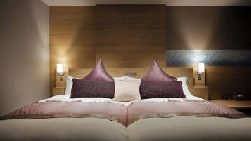 A neatly made bed with a textured blanket, two decorative pillows, and a wooden headboard. There are two wall-mounted nightstands with lamps.
