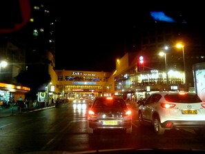 Una concurrida calle urbana de noche con escaparates visibles, incluyendo Zara y Casto.