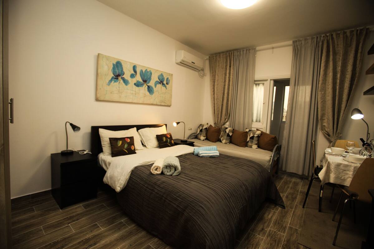 Una habitación de hotel con una cama grande, una mesita de noche, un escritorio con silla y un cuadro en la pared.