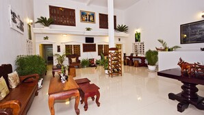 A spacious lobby with high ceilings, wooden furniture, and potted plants. - Overflow Guesthouse (Siem Reap)