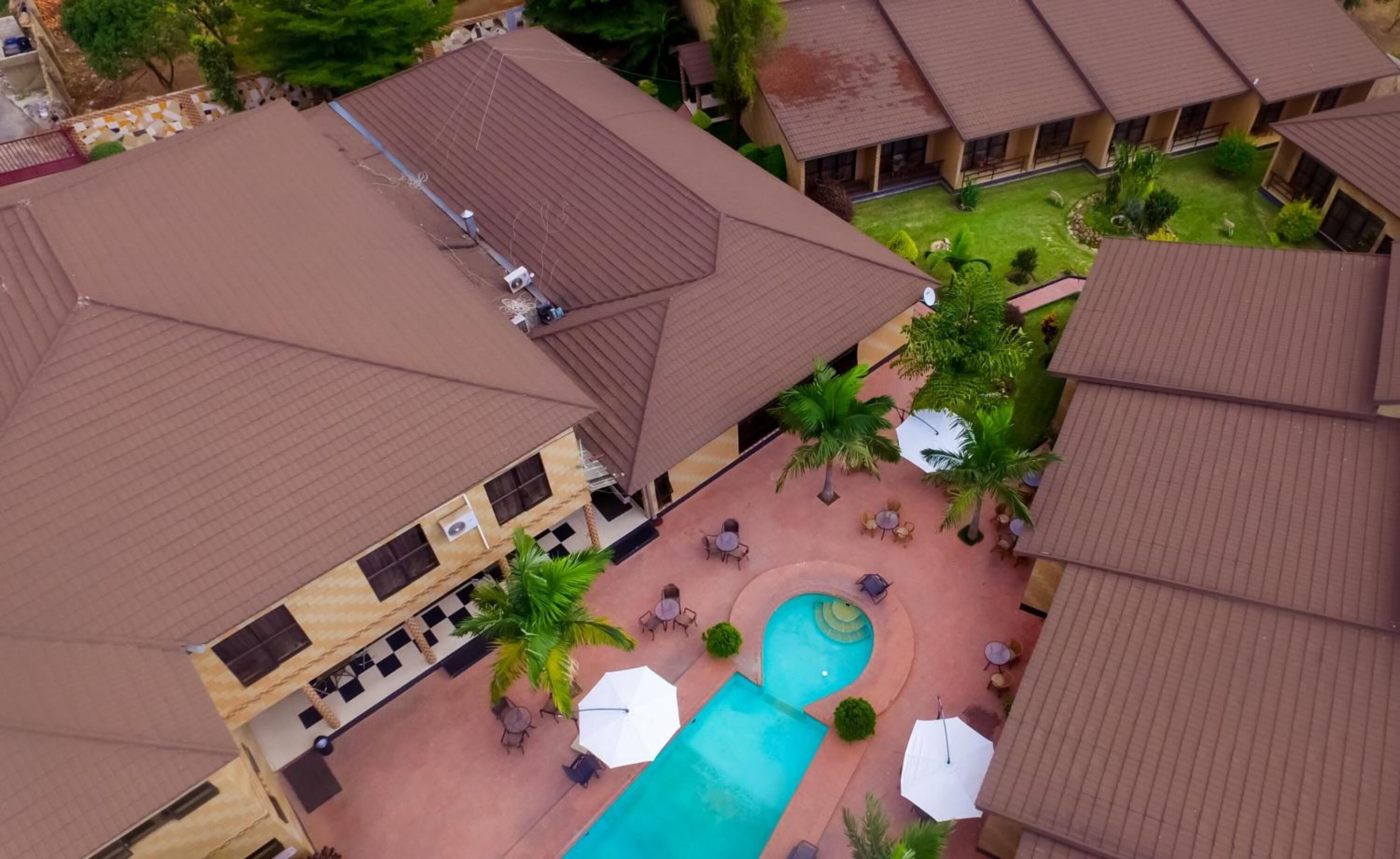 An aerial view of a hotel with multiple buildings, a swimming pool, and outdoor seating areas.
