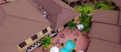 An aerial view of a hotel with multiple buildings, a swimming pool, and outdoor seating areas.