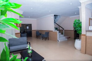 A lobby with a sofa, chairs, a coffee table, a staircase, and a potted plant. - Mika Hotel, Kabulonga (Lusaka)