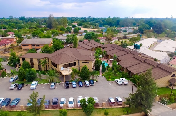 A residential area with multiple houses, a parking lot, and a large building with a sloped roof. - Mika Hotel, Kabulonga (Lusaka)