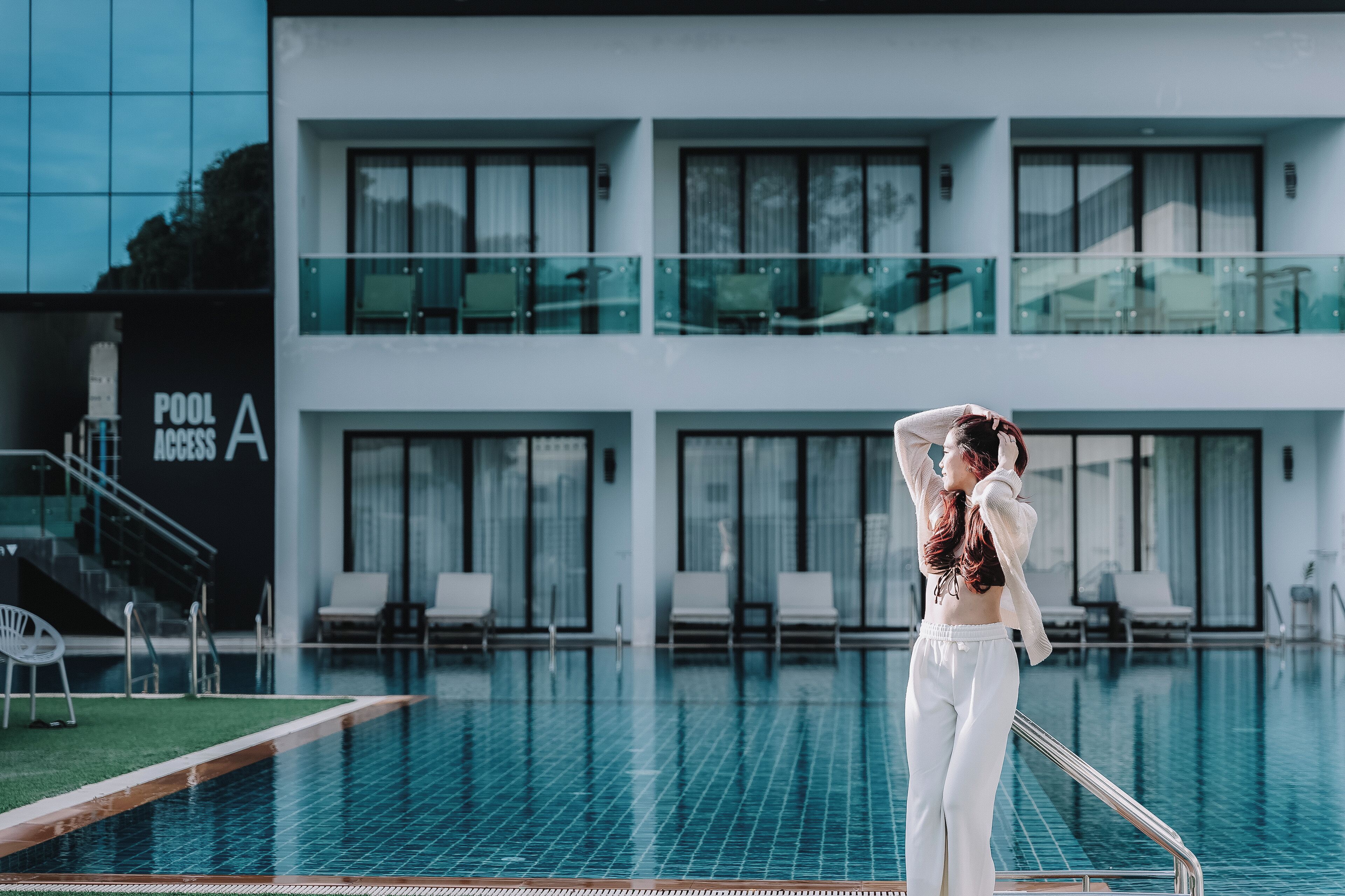 A modern hotel with a pool area, including lounge chairs and a glass balustrade.