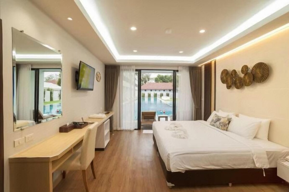 A hotel room with a bed, desk, and a large window.