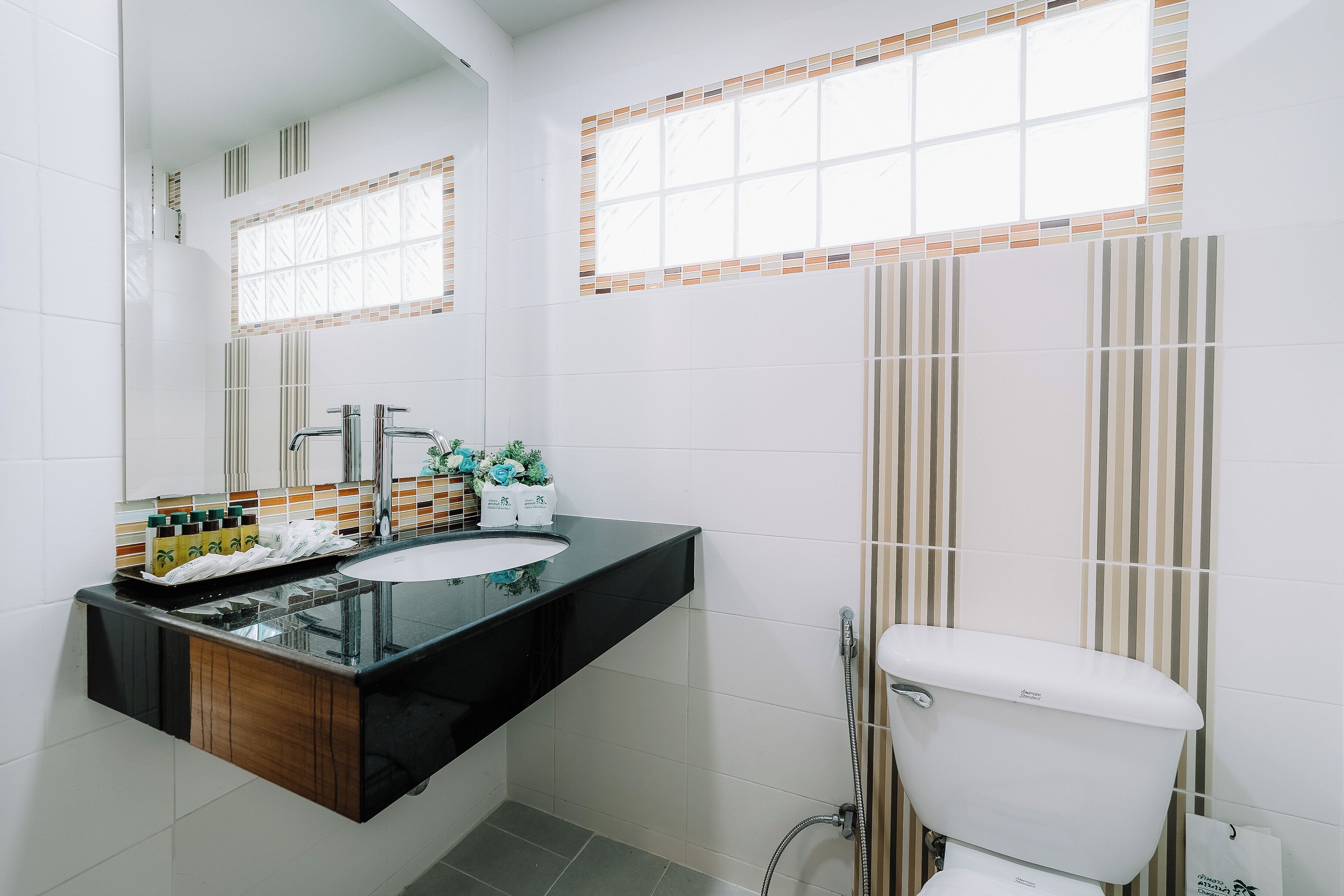 Un baño moderno con encimera negra, lavabo blanco y inodoro blanco.