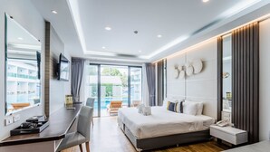 A modern hotel room with a bed, desk, and chair, a large window, and a view of the outdoors.