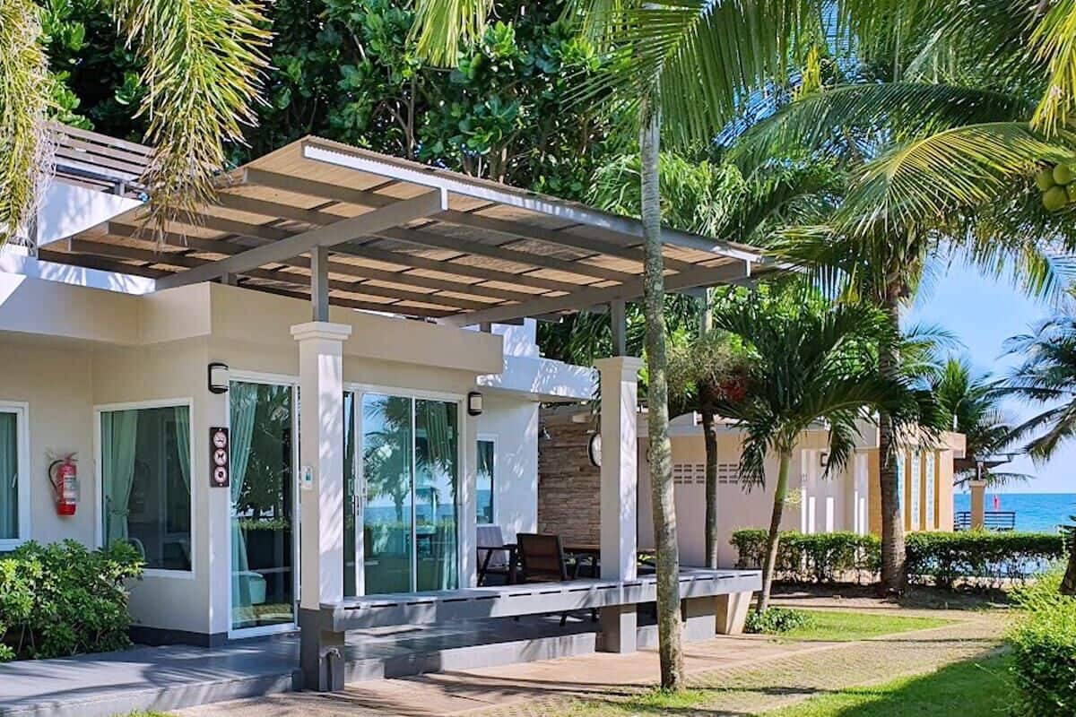 A modern resort with a covered outdoor seating area, a pool, and a view of the ocean.
