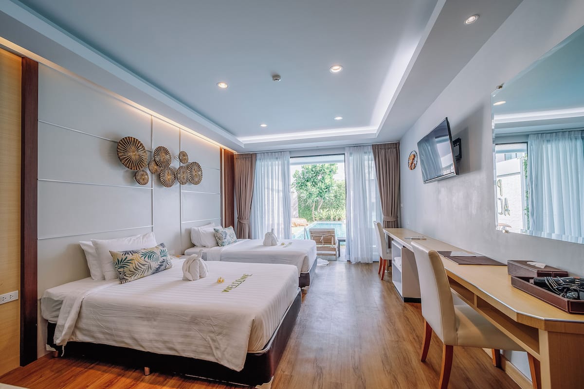 A hotel room with two beds, a desk, and a TV.