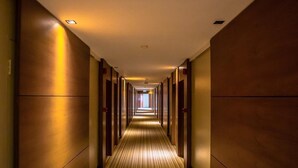 Ein langer, schmaler Hotelgang mit Holzwänden und einem Streifenmuster-Teppich.