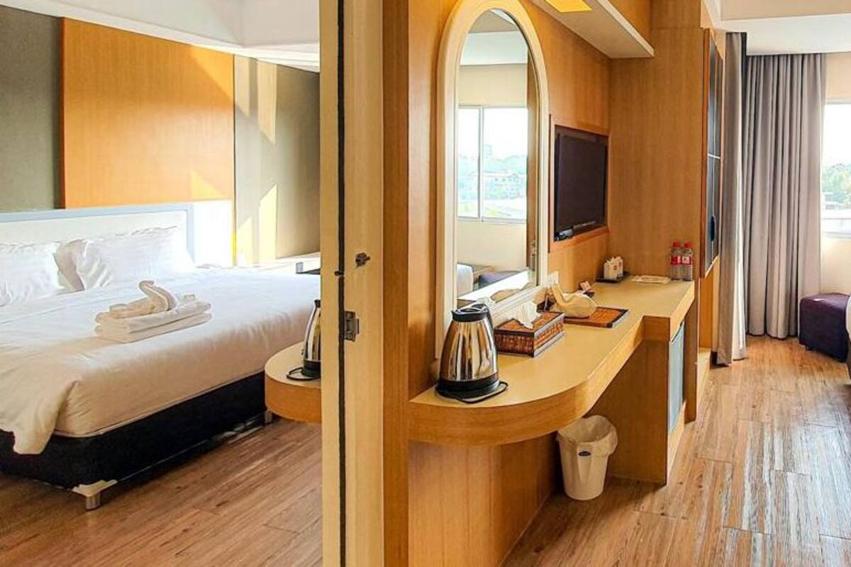A hotel room with two beds, a desk with a TV, and a view of the outdoors.