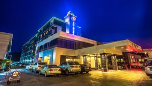 Ein modernes Hotel mit einem markanten Glockenturm und mehreren Parkplätzen.