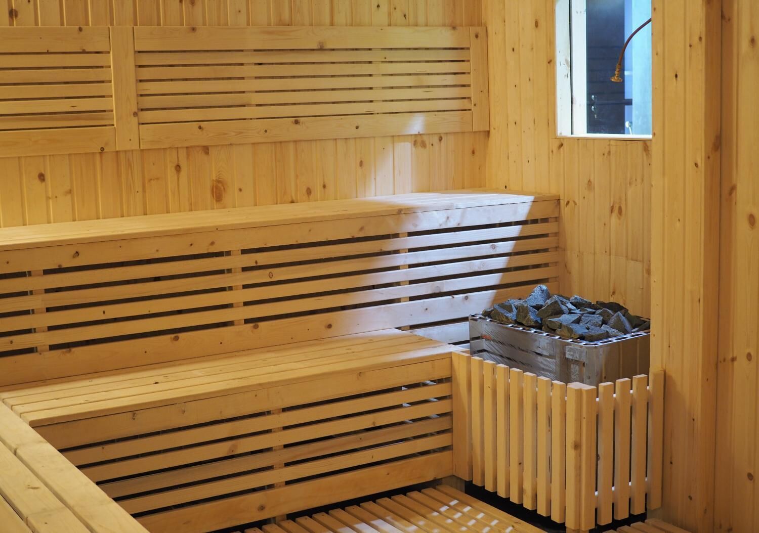 Una sauna con bancos de madera y un calentador de piedra.