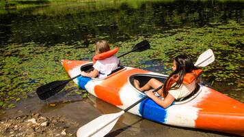 Two people in a canoe on a calm river with lily pads.