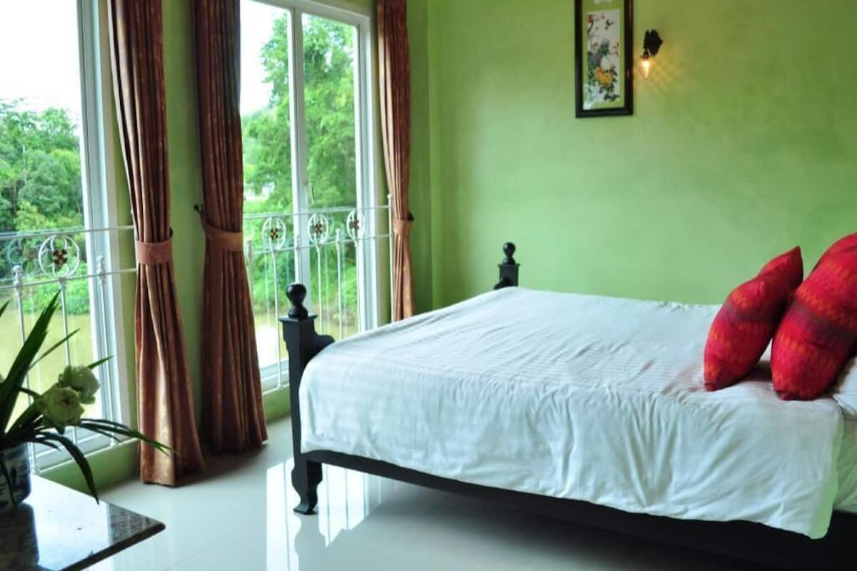 A bedroom with a bed, curtains, a window, and a plant.