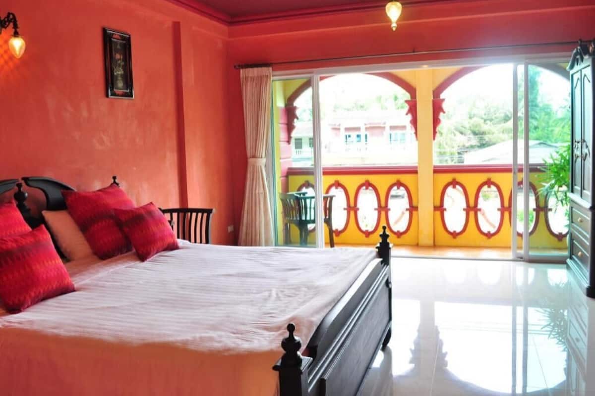 A room with a bed, a window with curtains, and a view of a building outside.